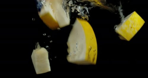Des tranches de melon tombent dans l'eau avec des bulles d'air.