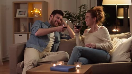 Glückliches Paar trinkt am Abend zu Hause Rotwein 4
