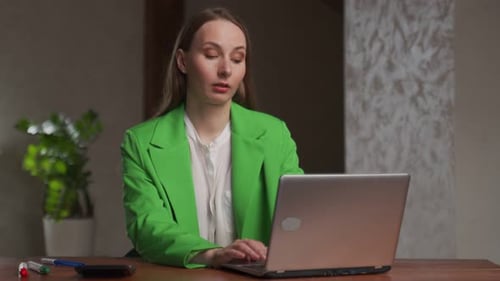 Tired Woman Works on Laptop at Table in Office Taking Break