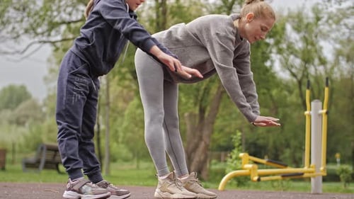 Mother and Daughter Doing Exercises on Open Air Sport Playground