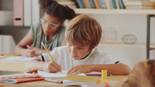 Child Drawing in School Classroom at Desk