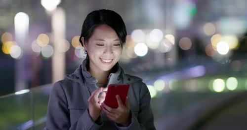 Woman use of mobile phone in the street at night
