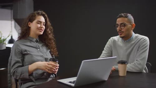 Young Adults Collaborating on Laptop in Modern Office