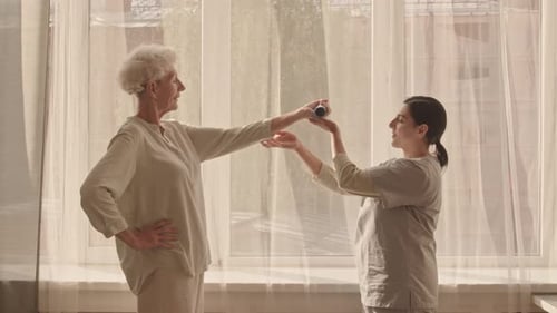 Energetic Senior Woman Exercising with Caregiver Indoors