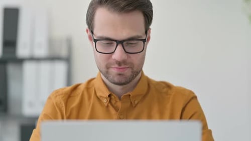 Close Up of Young Man Working on Laptop in Office