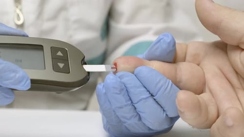 Doctor measures man’s blood sugar level using glucose meter