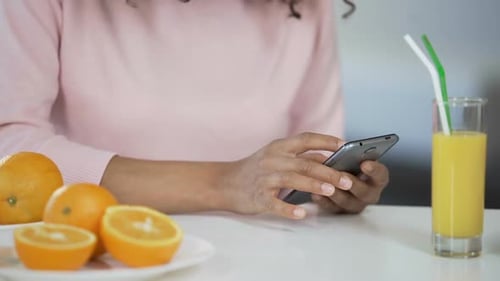 Person Using Phone with Juice and Oranges