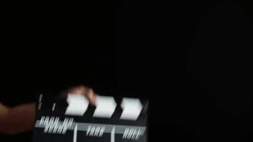 Hände mit einem Filmklapperbrett, auf Schwarz, Nahaufnahme