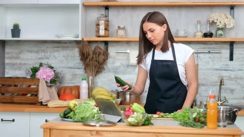 Woman Chopping Vegetables in Modern Kitchen, Following Recipe