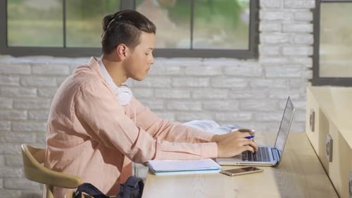 Young Adult Studying At Desk With Laptop