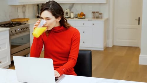 Woman Works on Laptop and Drinks Juice