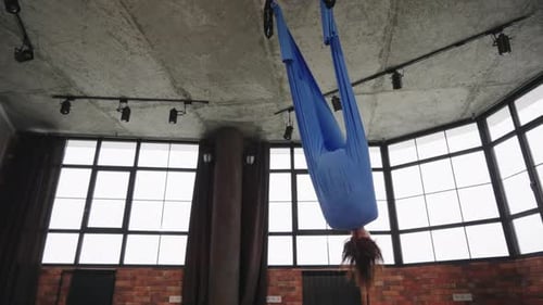 Woman in Hammock Practicing Fly Yoga in Studio