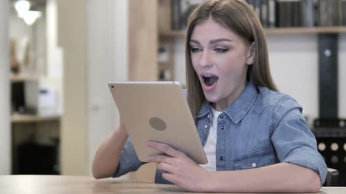 Woman Excitedly Using Tablet at Home