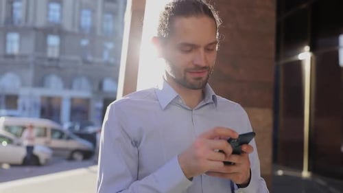 Business Man Using Mobile Phone Outdoors On Sunny Day At Street