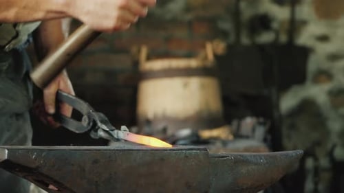Blacksmith Shaping Hot Metal on Anvil in Workshop