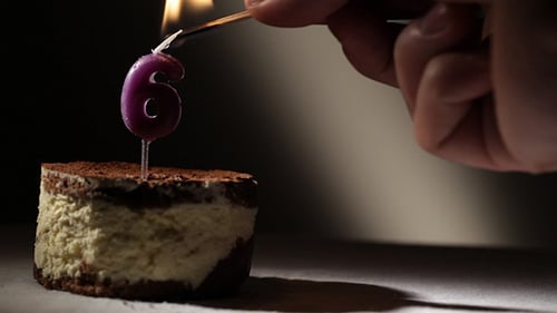 Burning Number Six Candle on Decadent Dessert