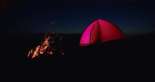Campfire and Glowing Tent at Night in Wilderness