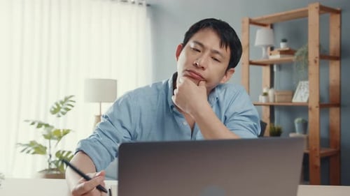 Asia guy casual wear using laptop online in living room at home office. Working from house.