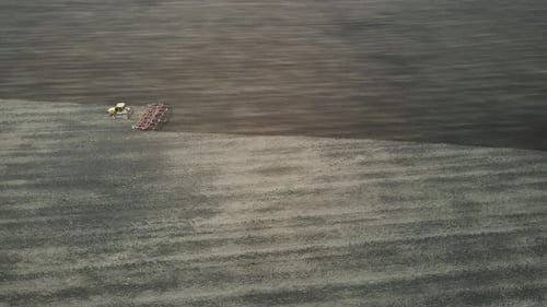 Luftaufnahme eines modernen gelben Traktors, der trockene landwirtschaftliche Felder pflügt und Land für die Aussaat vorbereitet
