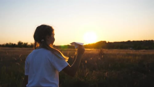 Carefree Child Walking with Paper Airplane Through Grass Field
