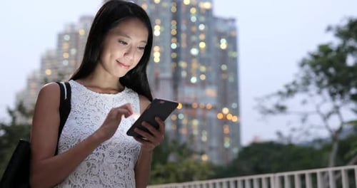 Woman using smart phone in city at night
