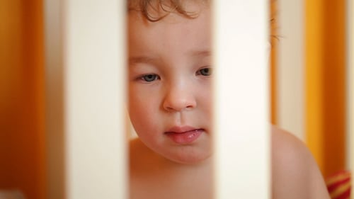 Close-Up of Adorable Child in Crib Indoors