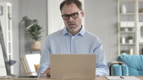 Frustrated Man Working on Laptop in Bright Office