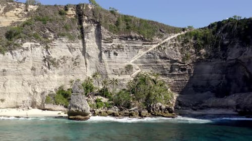 Hut inside vegetation patch at Diamond Beach in Nusa Penida island Indonesia, Aerial dolly left shot