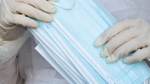 Stack of Surgical Masks Held by Gloved Hands