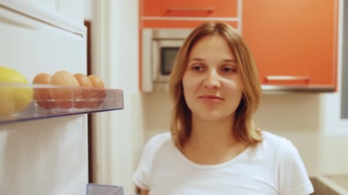 Woman Opens Fridge Looking at Food and Ingredients