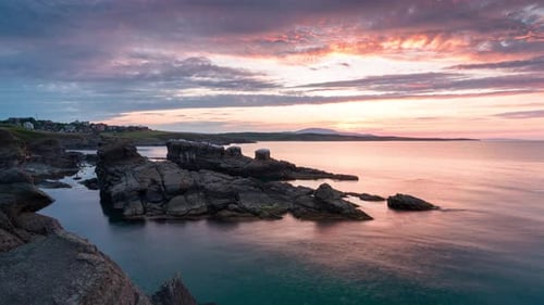 Time lapse with colorful sunset sky at rocky coastline