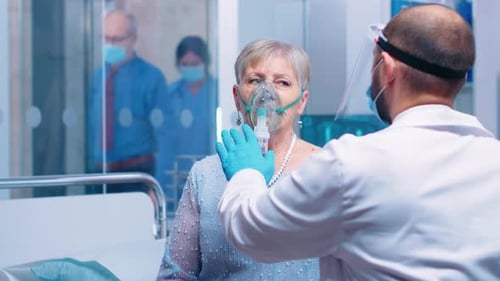 Doctor Adjusting Oxygen Mask of Hospitalized Woman