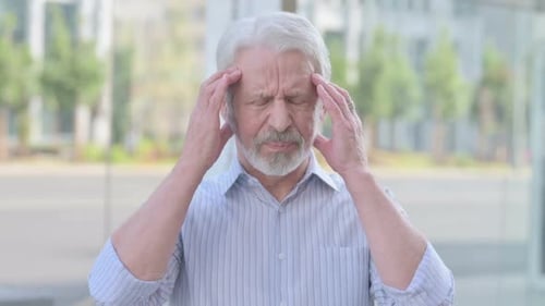 Senior Man Rubbing Temples Due to Headache