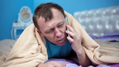 The man was sleeping under the covers taking cover with his head, woke up the phone