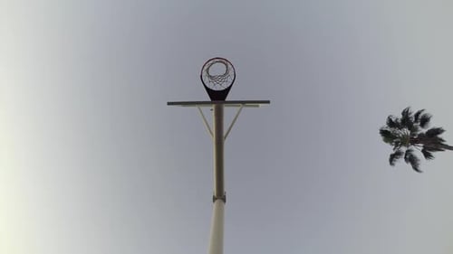 Vista panorâmica de minhoca de baixo ângulo de um jovem jogando basquete na praia.