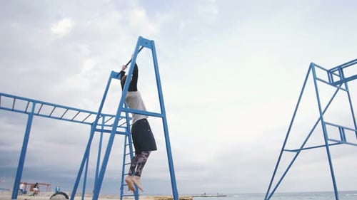 Young Man Doing Parkour Tricks on the Beach Near the Sea