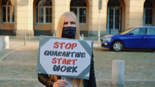 Woman Holds Sign Protesting Quarantine in Urban Setting