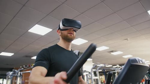 Young Strong Man Exercising on Treadmill at the Gym Wearing VR Glasses Slow Motion
