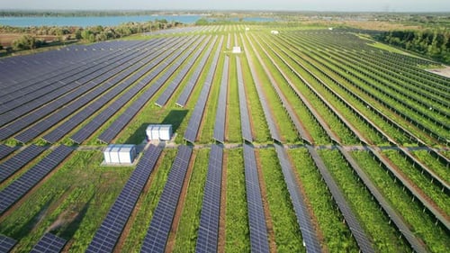 Luftbild Solarkraftwerk auf der grünen Wiese bei Sonnenuntergang Sonnenkollektoren in Reihe