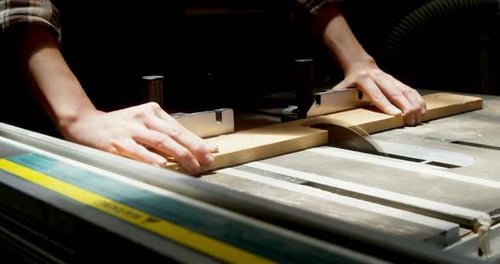Female welder using table saw on a wooden plank in workshop 4k