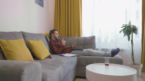 Man on Laptop Relaxing on Sofa at Home