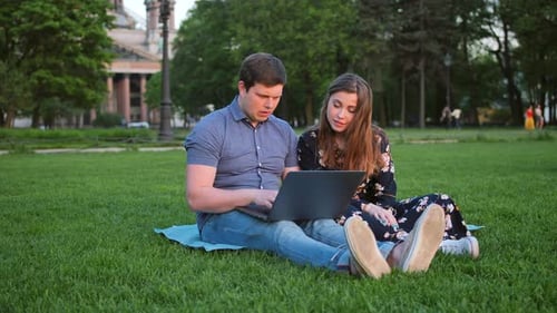 Couple Using Laptop Together in Urban Park