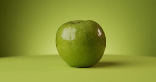 Delicious Rotating Green Apple Over a Colored Background