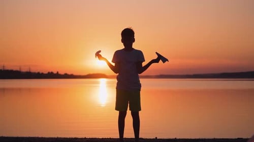 Boy Throws Paper Airplanes at Sunset Beach