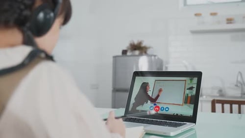 Asian little young girl learning online class from school teacher by digital remote internet at home