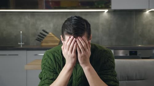 Portrait of Sad Man in Despair Has Mental Problems Sitting on the Couch in the Living Room