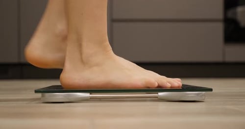 Woman Weighing Herself on Scale Close Up