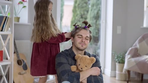 Girl Styles Dad's Hair with a Teddy Bear