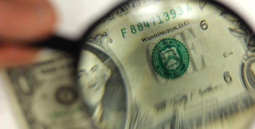 Examining Dollar Bill with Magnifying Glass Close Up