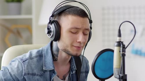 Man Singing and Playing Guitar in Home Studio